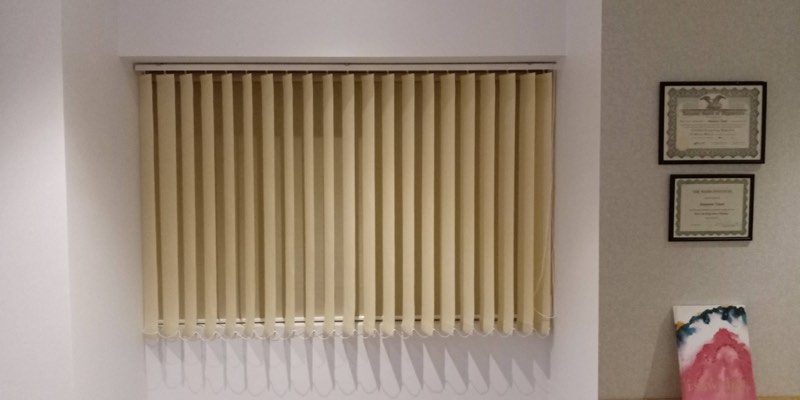 Cream vertical blinds beside framed certificates