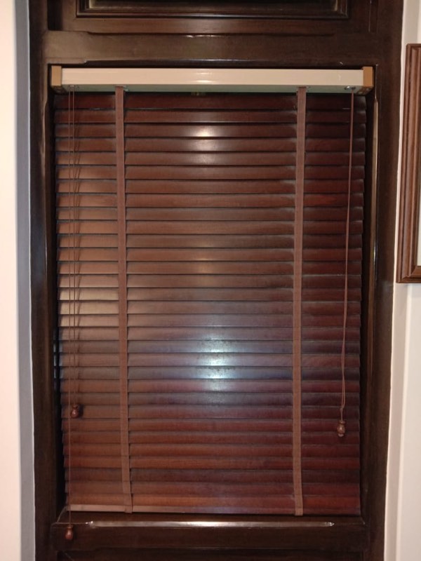 Dark wooden venetian blind on a tall window