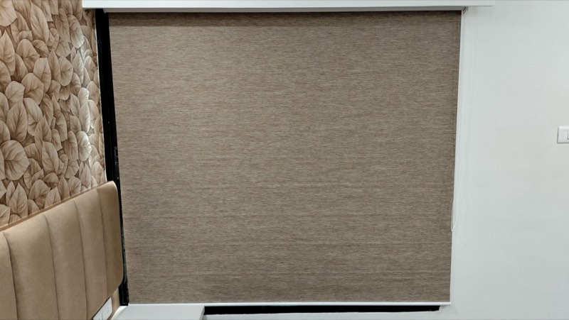 Linen roller blind beside a padded headboard